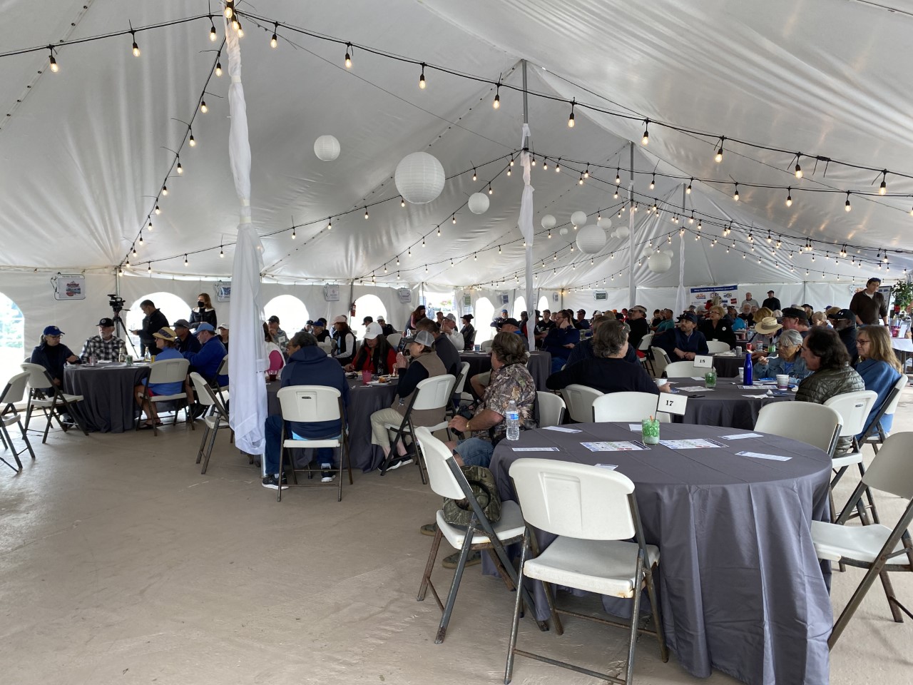 A picture from inside the event tent, with groups of people around circular tables