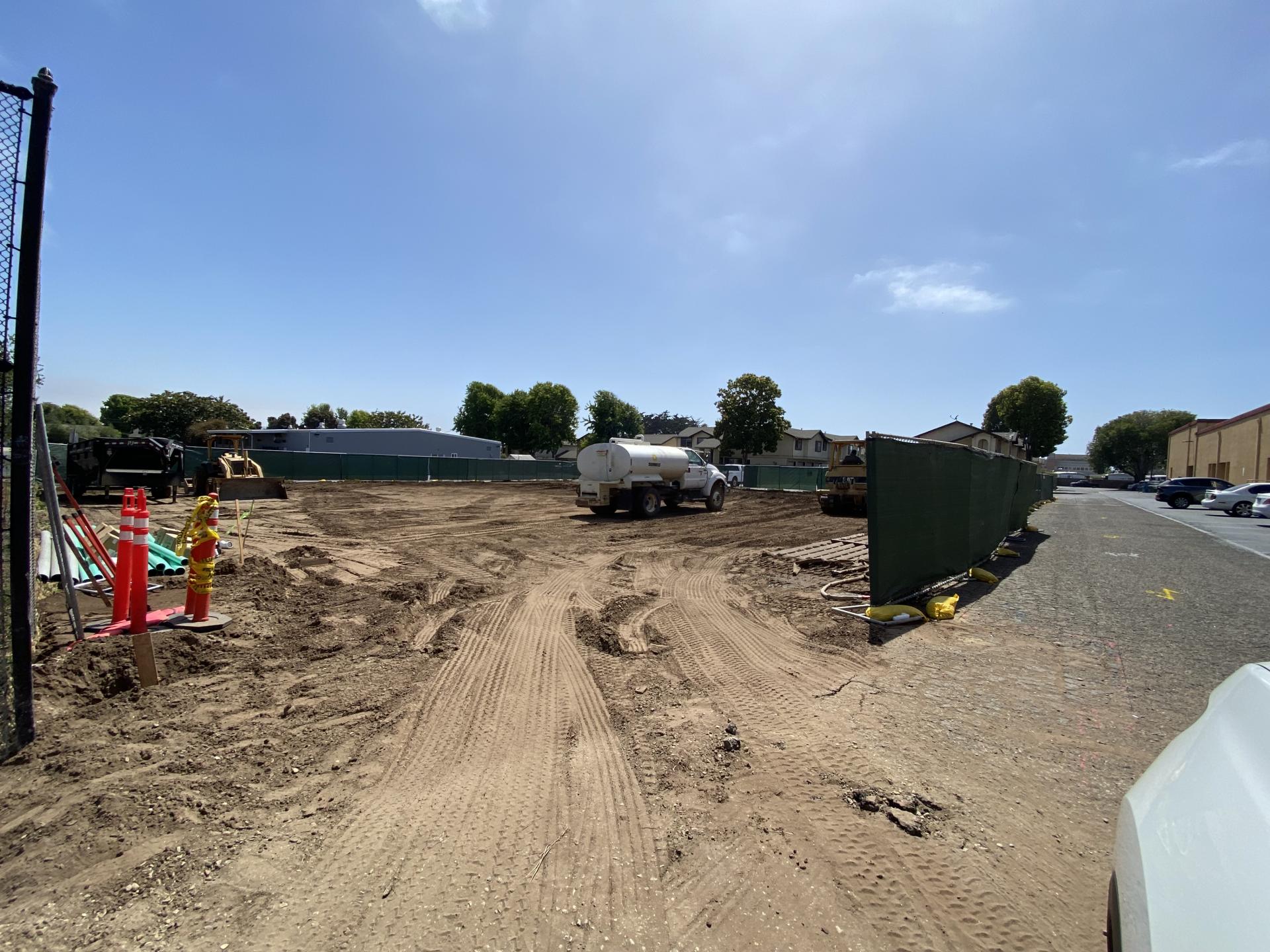 Construction equipment moving dirt at a lot on a sunny day